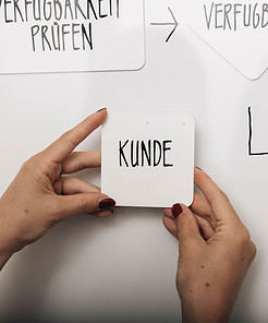 Eine Frau haelt eine quadratische magnetische von Proboard vor Whiteboard in den Händen